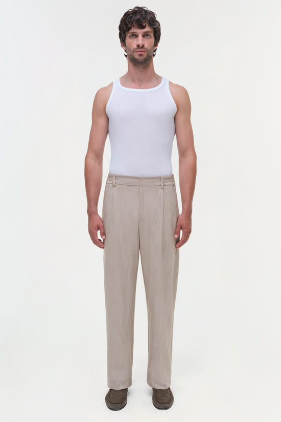 Man wearing beige striped Duncan pants with a white tank top and brown shoes.