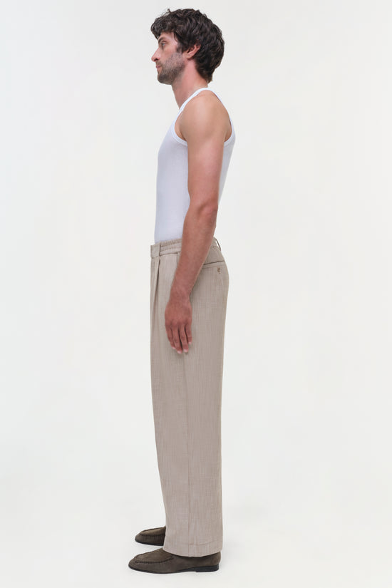Man wearing beige textured Duncan pants with white tank top, shown in profile view.