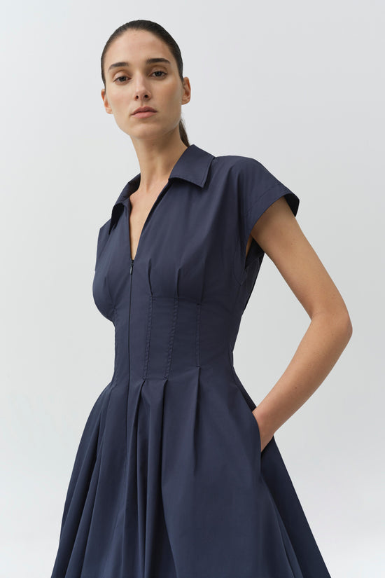 Navy cotton mini dress with collared neckline, short sleeves, front zip closure, and gathered bubble skirt with side pockets.