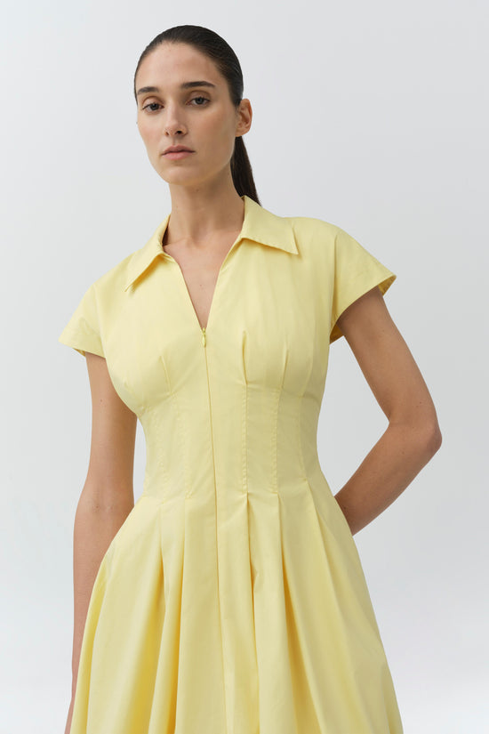 Yellow cotton mini dress with short sleeves, collared neckline, front zip closure, and pleated skirt.