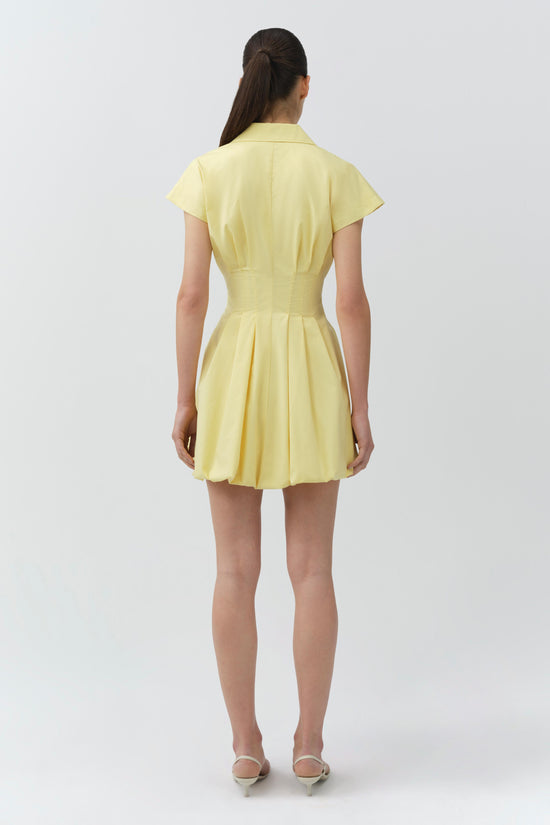 Yellow cotton bubble mini dress with short sleeves, collar, and pleated skirt, shown on model from back view.