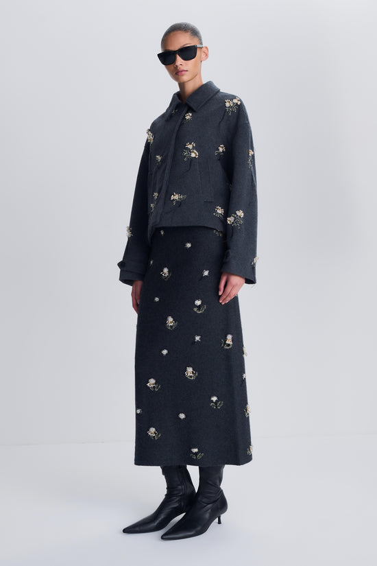 Dark wool jacket with scattered crystal and rhinestone embellishments throughout, worn with matching skirt.