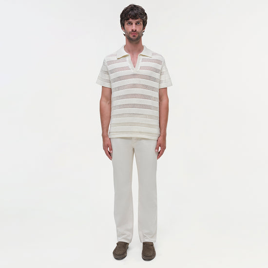 Man wearing cream and taupe striped mesh polo with short sleeves and V-neck collar, paired with cream pants.