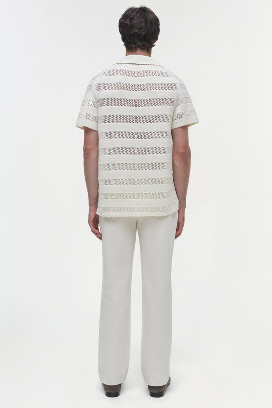 White short-sleeve mesh polo with horizontal stripes worn with white pants, shown from back view.