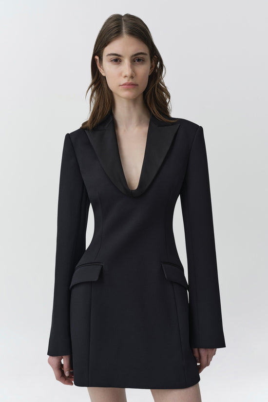 Black blazer mini dress with long sleeves, deep V-neckline, and flap pockets at the waist.