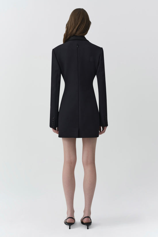 Black blazer mini dress with long sleeves and collar, shown from back view on model wearing black heels.
