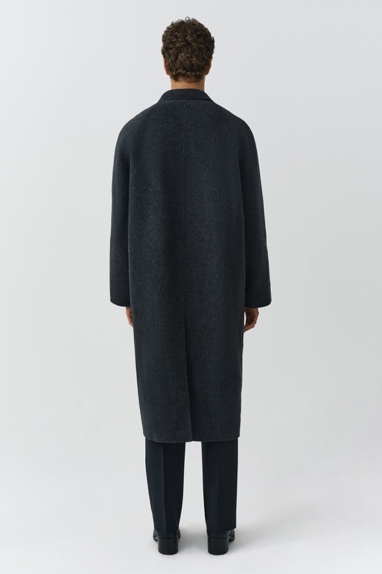Charcoal double breasted coat with oversized silhouette, shown from back on model wearing black trousers.
