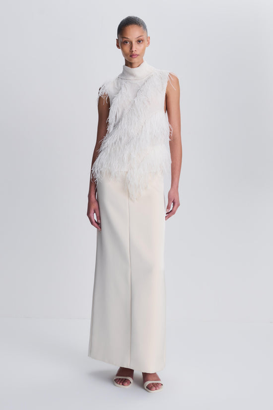 Woman wearing cream sleeveless top with feather detailing and matching cream trousers.