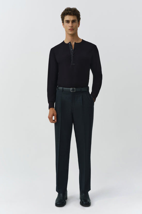 Man wearing black ribbed henley with button placket and dark trousers with belt.