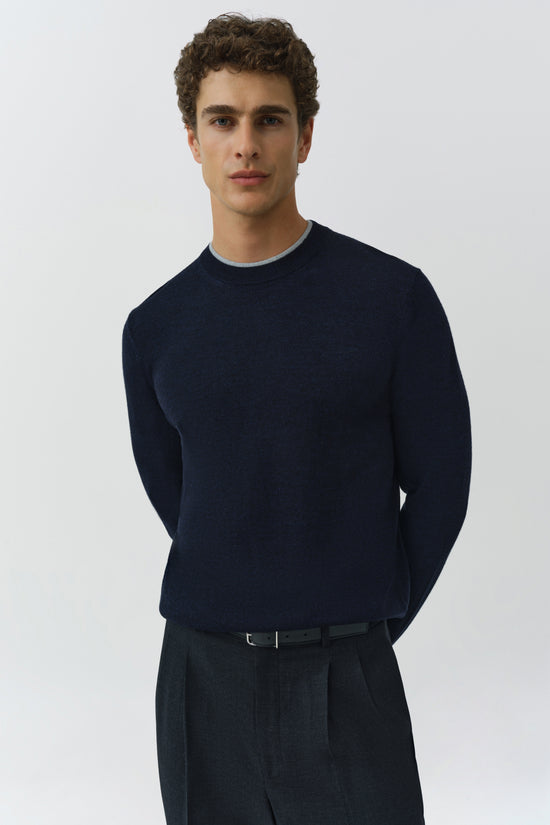 Man wearing dark navy crewneck sweater with ribbed collar and long sleeves.