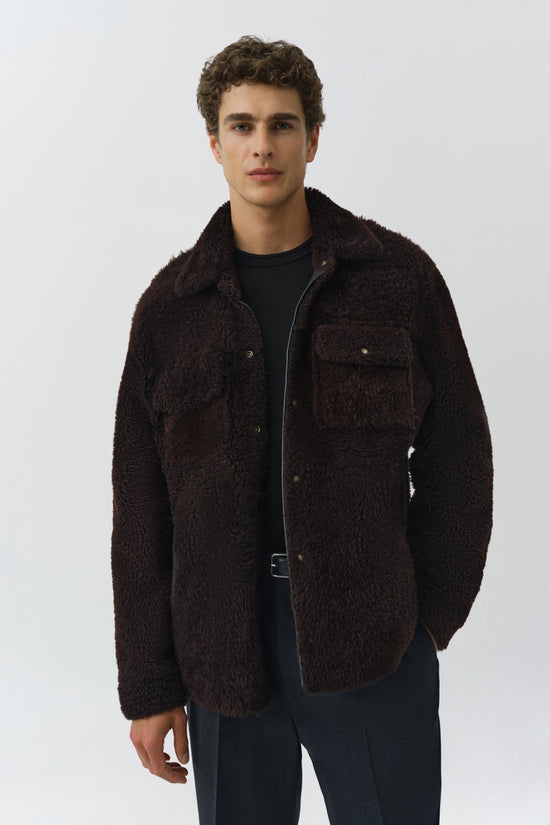 Man wearing dark brown textured shirt jacket with button front and chest pockets over black t-shirt.