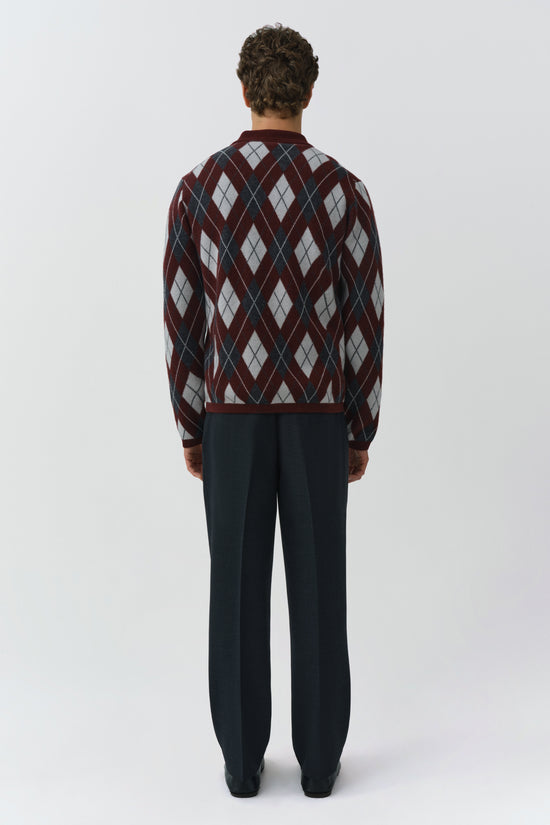 Burgundy argyle polo with gray and navy diamond pattern, paired with black trousers, shown from back view.