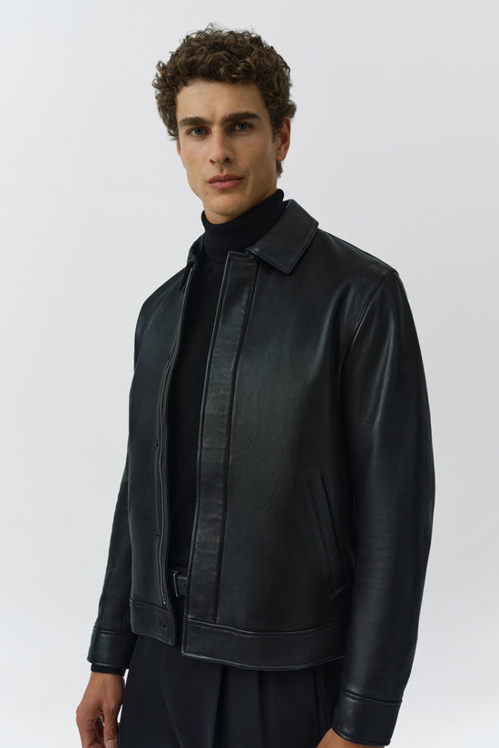 Black leather jacket with collared neckline, front zip closure, and side pockets on model.