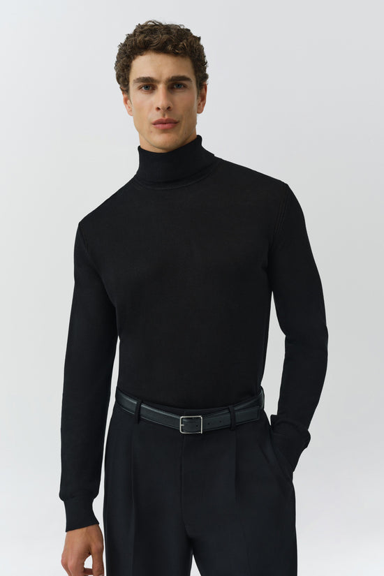 Black turtleneck with long sleeves on a model wearing dark trousers and a leather belt.