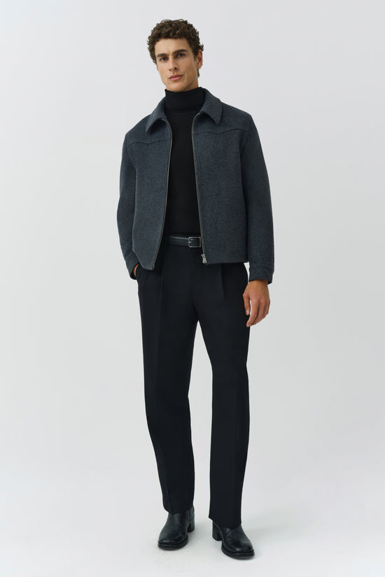 Man wearing charcoal wool jacket with wide collar over black turtleneck and black trousers.