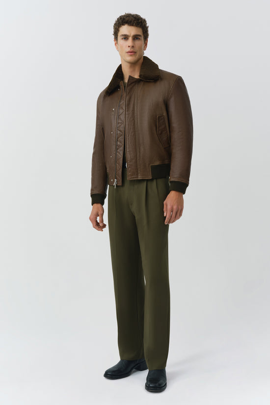 Brown leather jacket with collar, front zip closure, and ribbed knit cuffs on model.