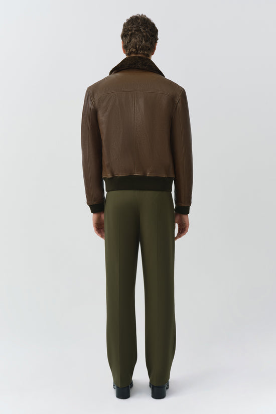 Brown leather jacket with black shearling collar and ribbed cuffs, shown from back view on model.