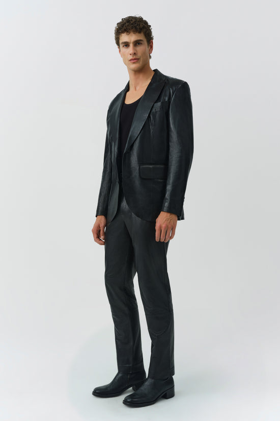 Black leather blazer with notched lapels and single chest pocket, worn with matching trousers.