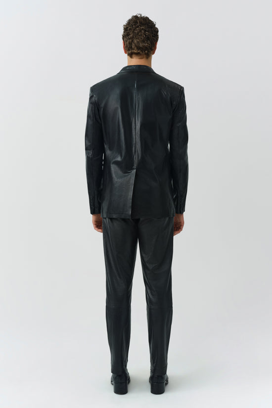 Black leather pants with a straight leg fit and platform sole boots, shown from the back on a model.