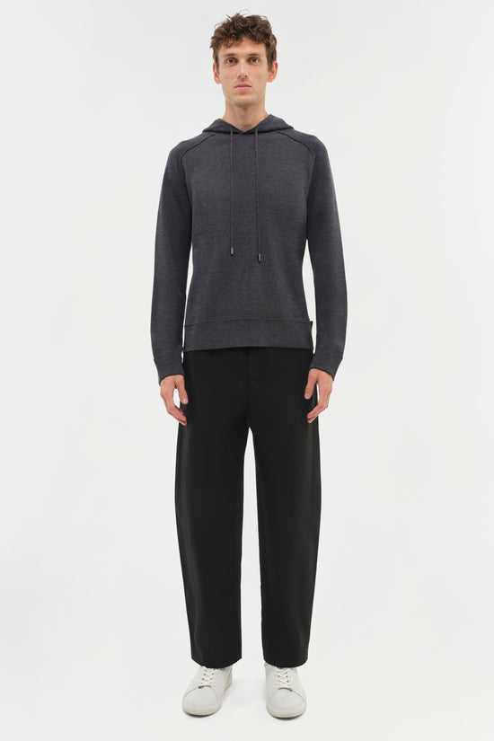 Charcoal gray hoodie with drawstring worn with black trousers and white sneakers.