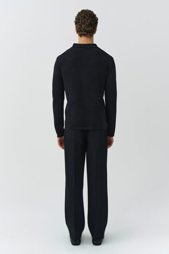 Man wearing black Reynolds knit polo with long sleeves and matching black pants, shown from back.