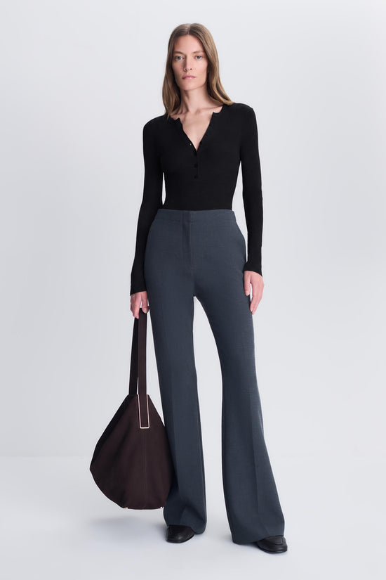 Black silk cashmere Henley bodysuit with long sleeves and V-neckline worn with gray flared pants.