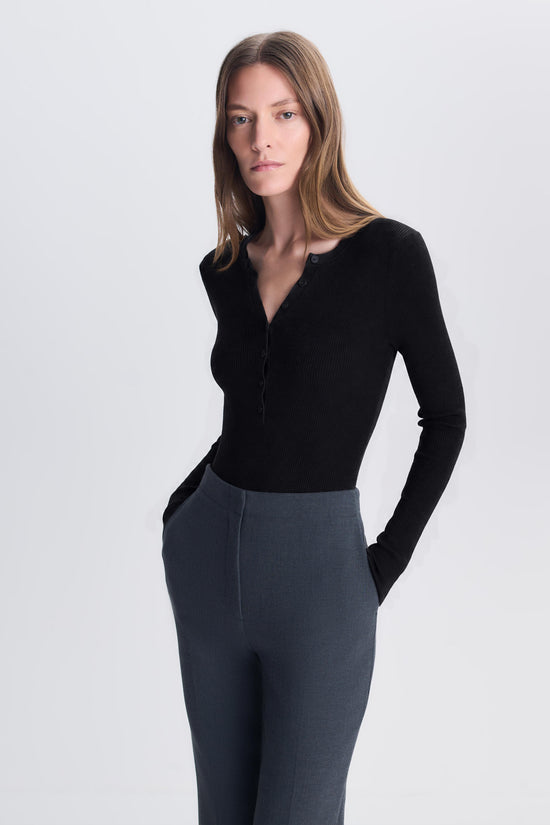 Black ribbed henley bodysuit with long sleeves and button front, worn with gray trousers.