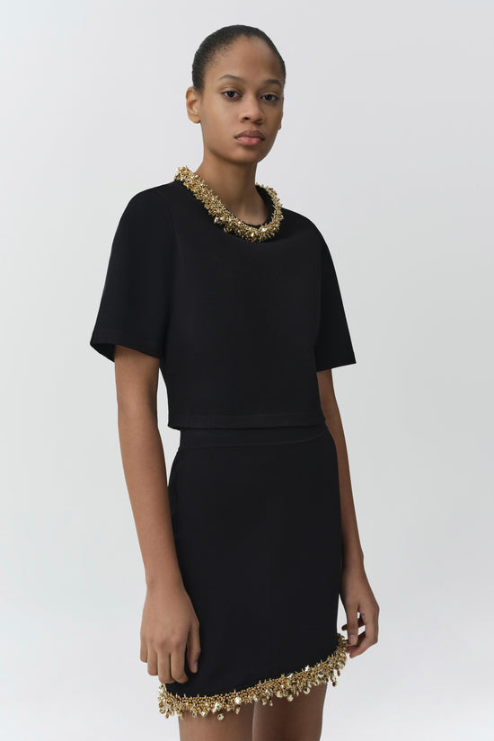 Black knit top with short sleeves and gold beaded neckline and hem detail.