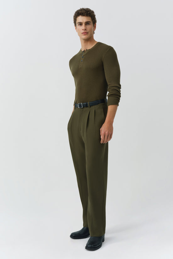 Olive green henley with button placket and long sleeves, styled with matching trousers and dark belt.