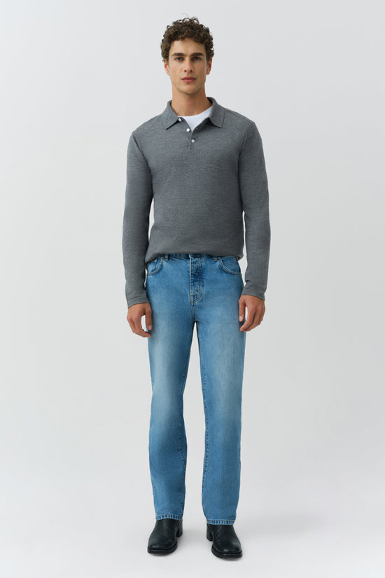 Man wearing gray long-sleeve knit polo with collar and button placket, paired with blue jeans and black shoes.
