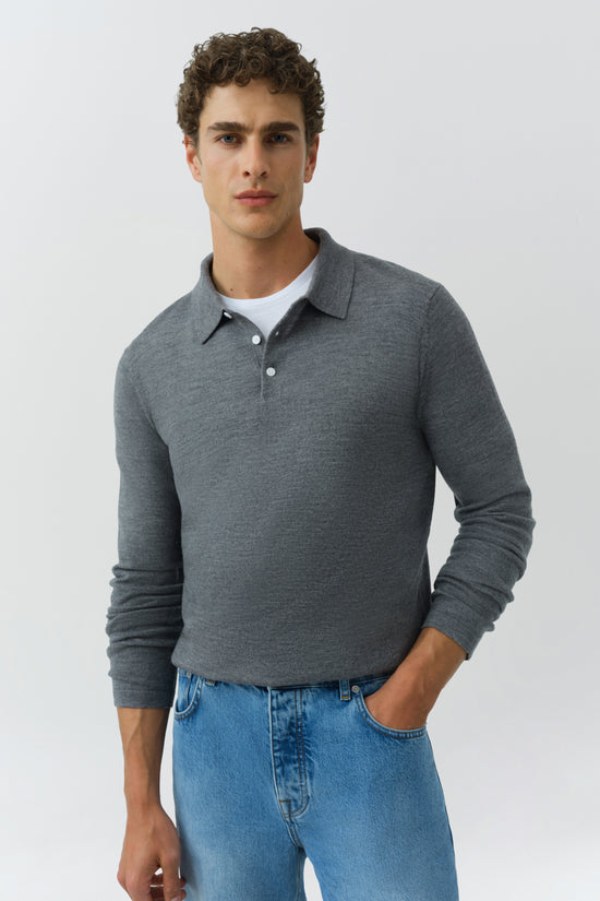 Man wearing charcoal gray knit polo with white buttons and collar, paired with blue denim jeans.