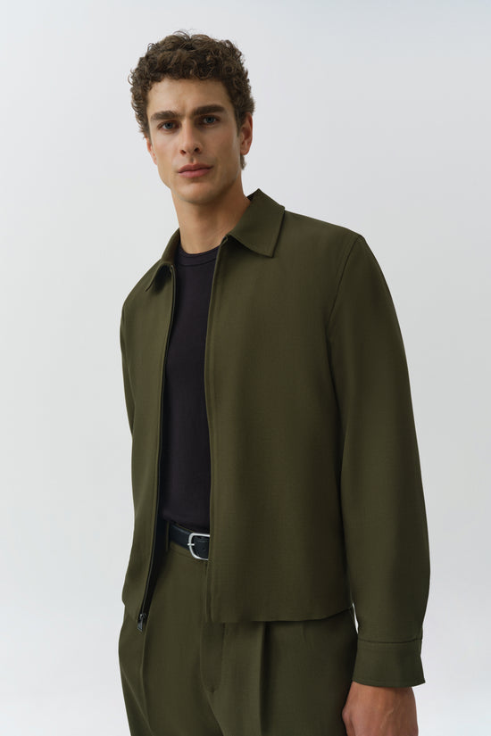 Man wearing olive green Sidney Jacket with collar and zip closure over navy t-shirt.