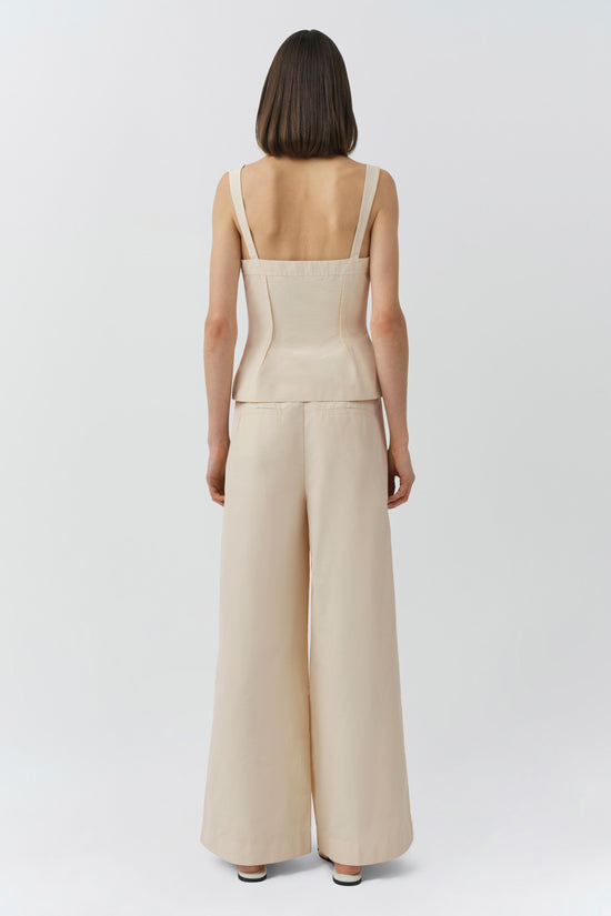 Cream cotton bustier top with thin straps and open back, paired with matching wide-leg trousers.