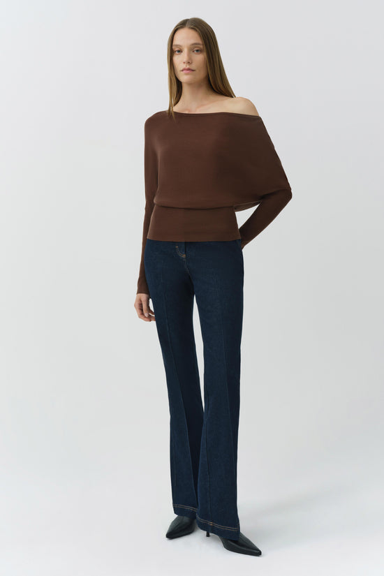 Brown off-shoulder cropped sweater with ribbed waistband worn with dark blue jeans.