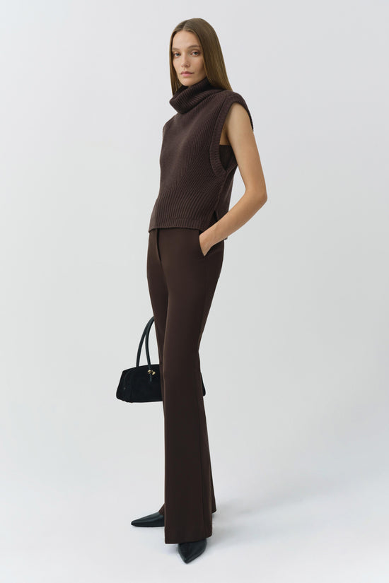 Brown ribbed sleeveless turtleneck top paired with dark brown flared pants and black ankle boots.