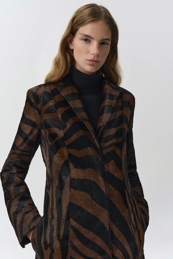 Brown and black zebra-striped calf hair coat with notched lapels worn over a black turtleneck.