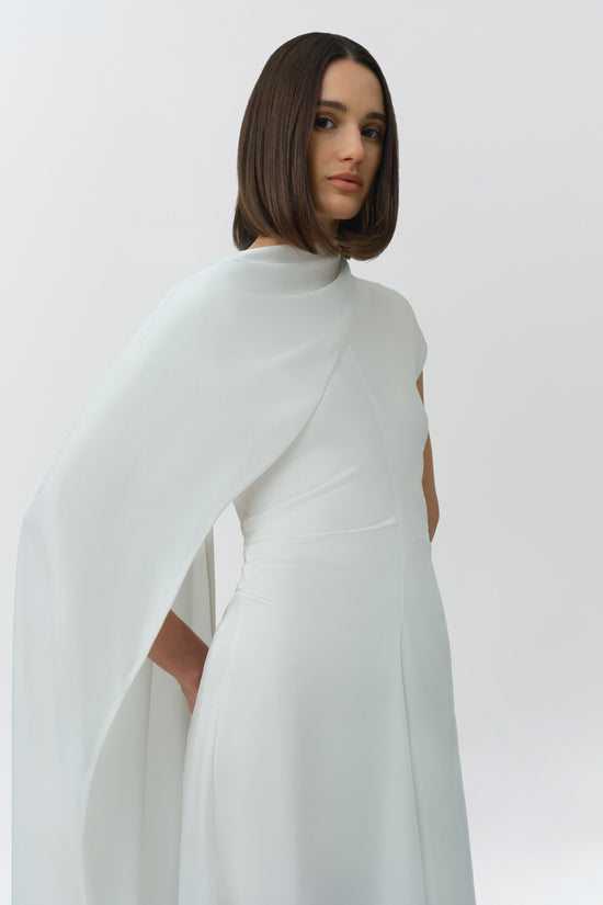 White satin midi dress with attached flowing cape detail, shown from back view on model.