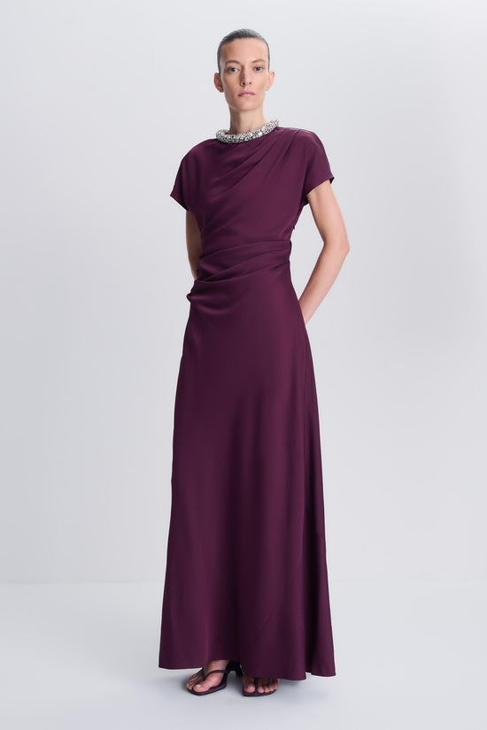 Burgundy satin gown with short sleeves, embellished neckline, ruched waist, and floor-length skirt.