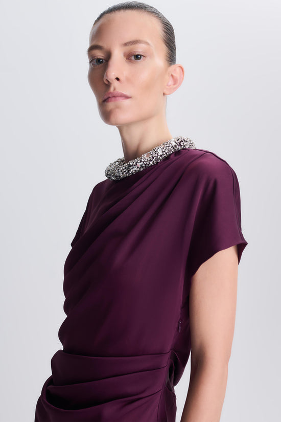 Burgundy satin gown with short sleeves, jeweled neckline, and ruched waist detail on model.