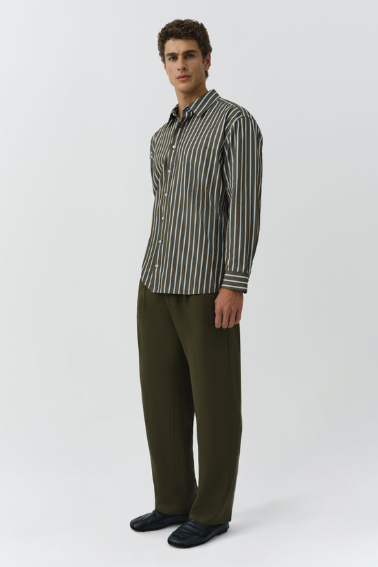 Man wearing charcoal striped oversized button-up shirt with olive pants and black slides.