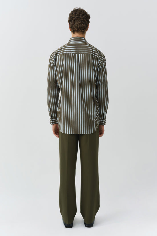 Oversized shirt with vertical stripes in olive and white, worn with matching olive pants.
