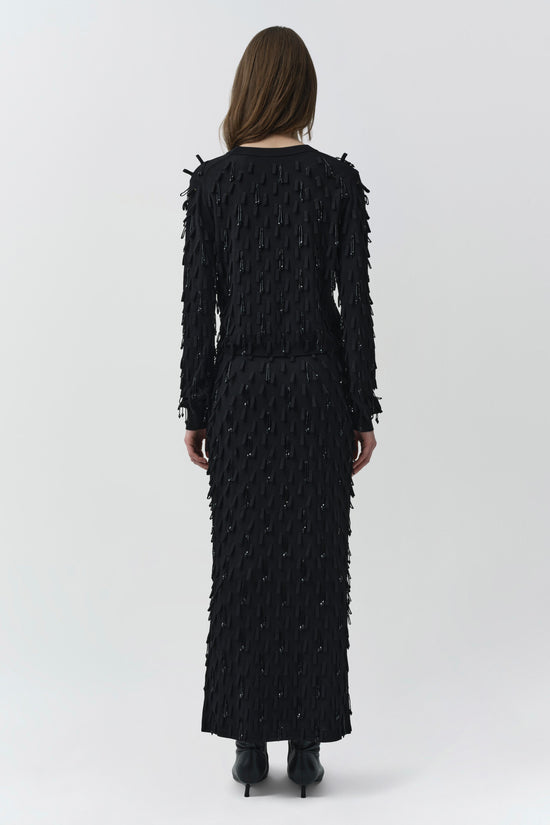 Black knit top with allover beaded and fringe embellishments, shown from back on model.