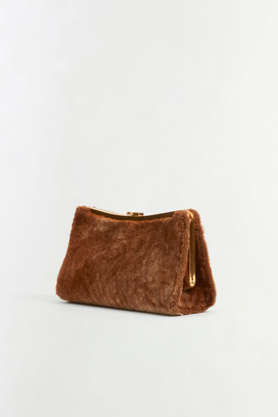 Tan shearling clutch with gold-tone metal frame and tassel charm.