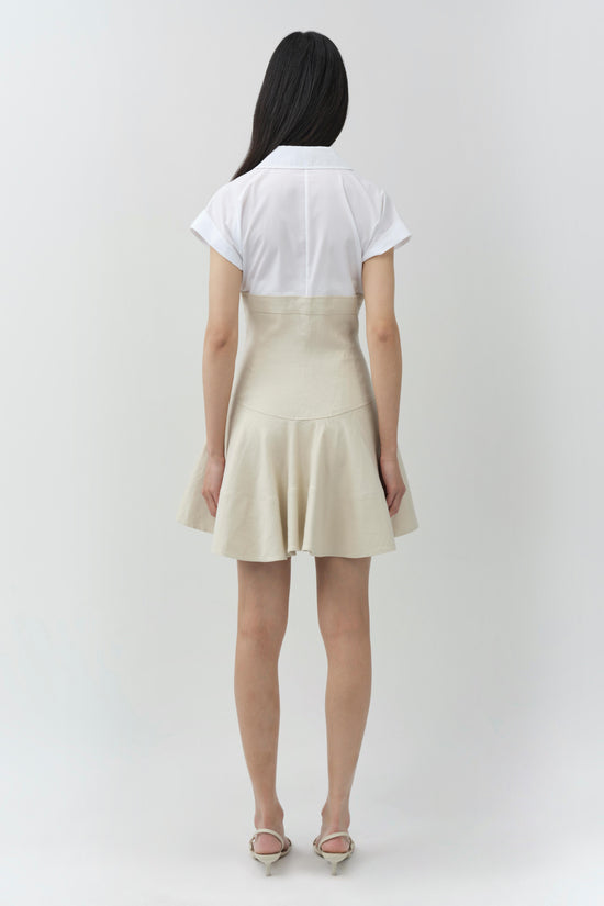 Woman wearing a white short-sleeve linen dress with a cream-colored skirt portion, shown from behind.