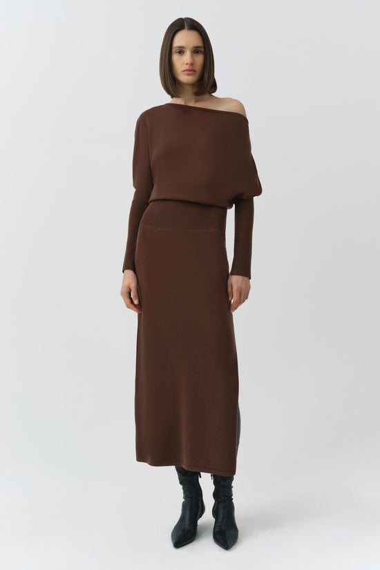 Brown off-shoulder midi dress with long sleeves and bloused top, worn with black boots.