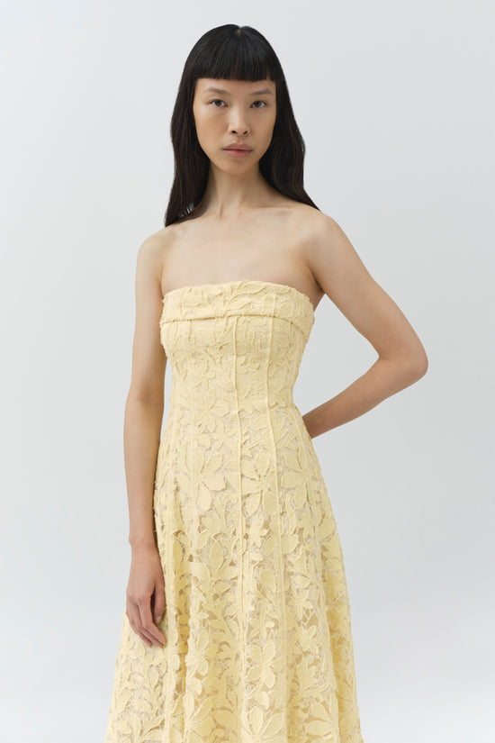 Pale yellow lace bustier midi dress with strapless neckline on model with long black hair.