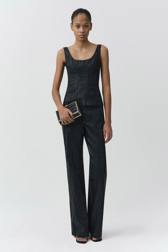 Dark coated denim trousers with straight legs, worn with matching sleeveless top and small clutch.