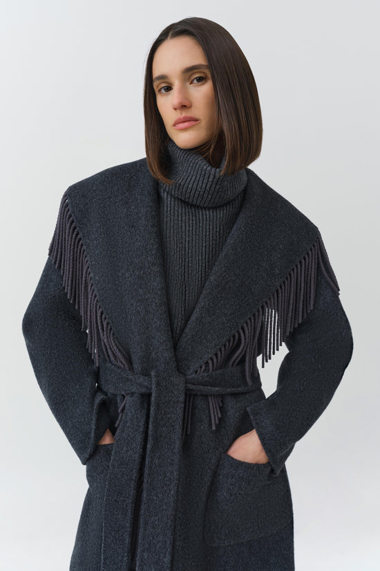 Charcoal wool coat with fringe trim on shoulders and sleeves, belt at waist, and front pockets.