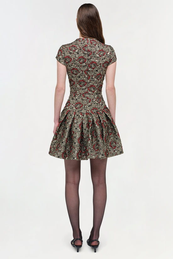 Short-sleeved mini dress with red and gold floral jacquard pattern and fitted bodice with pleated skirt, shown from back.