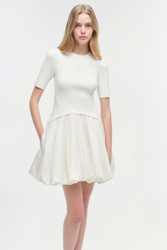 White ribbed knit mini dress with fitted elbow-length sleeves and full skirt bottom.